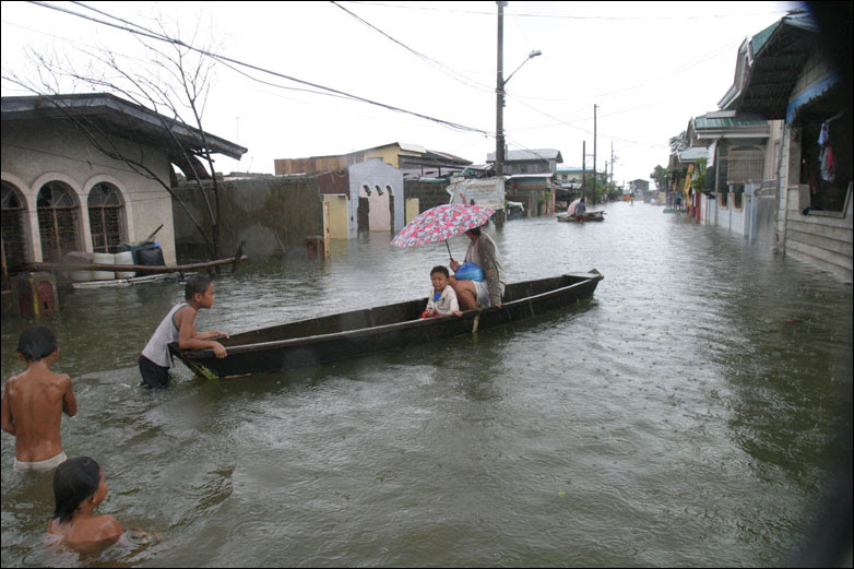 Residents use a boat for transport on the flooded streets in Dampalit north of Manila