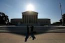 Two men talk as the sun rises over the Supreme Court in Washington