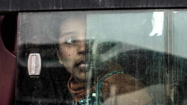 An Iraqi girl looks out the window of a bus transporting her to a nearby camp for internally displaced people.