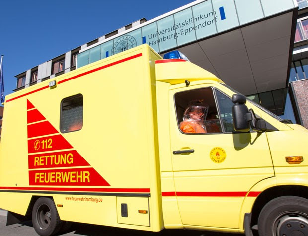 Pessoa em roupa especial é vista em ambulância na entrada do hospital Eppendorf, em Hamburgo, na Alemanha, nesta quarta-feira (27), enquanto levava um médico infectado pelo ebola em Serra Leoa para tratamento no local (Foto: dpa,Georg Wendt/AP)