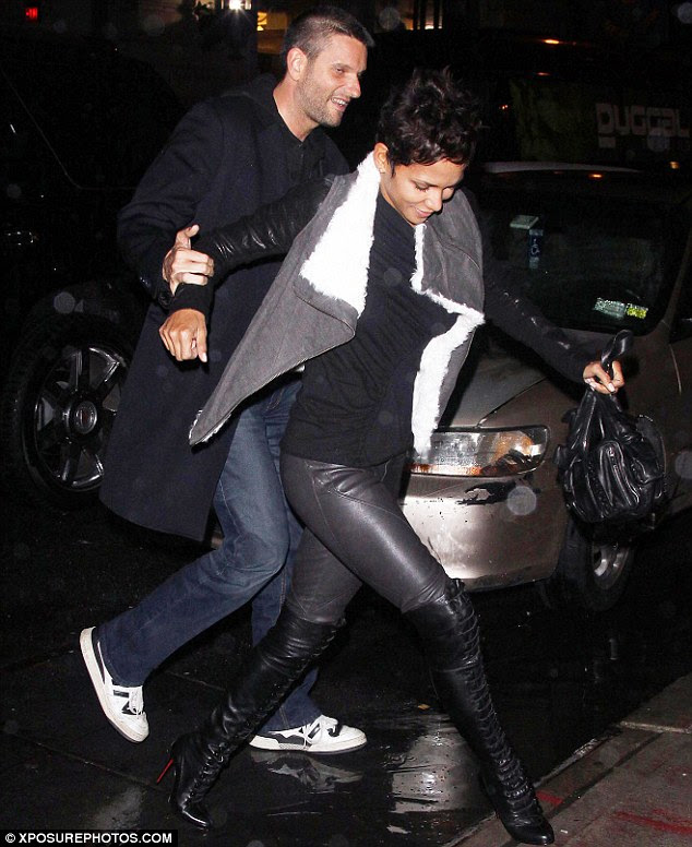 Careful! Halle is helped by a male friend as she takes care not to get her Christian Louboutin boots wet by jumping over a deep puddle