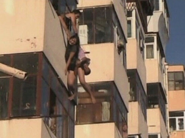 Um homem da província chinesa de Heilongjiang, que estava na varanda de sua casa, conseguiu pegar em plena queda uma mulher de 20 anos que pulou do apartamento acima, em uma aparente tentativa de suicídio. (Foto: Reuters/CCTV)