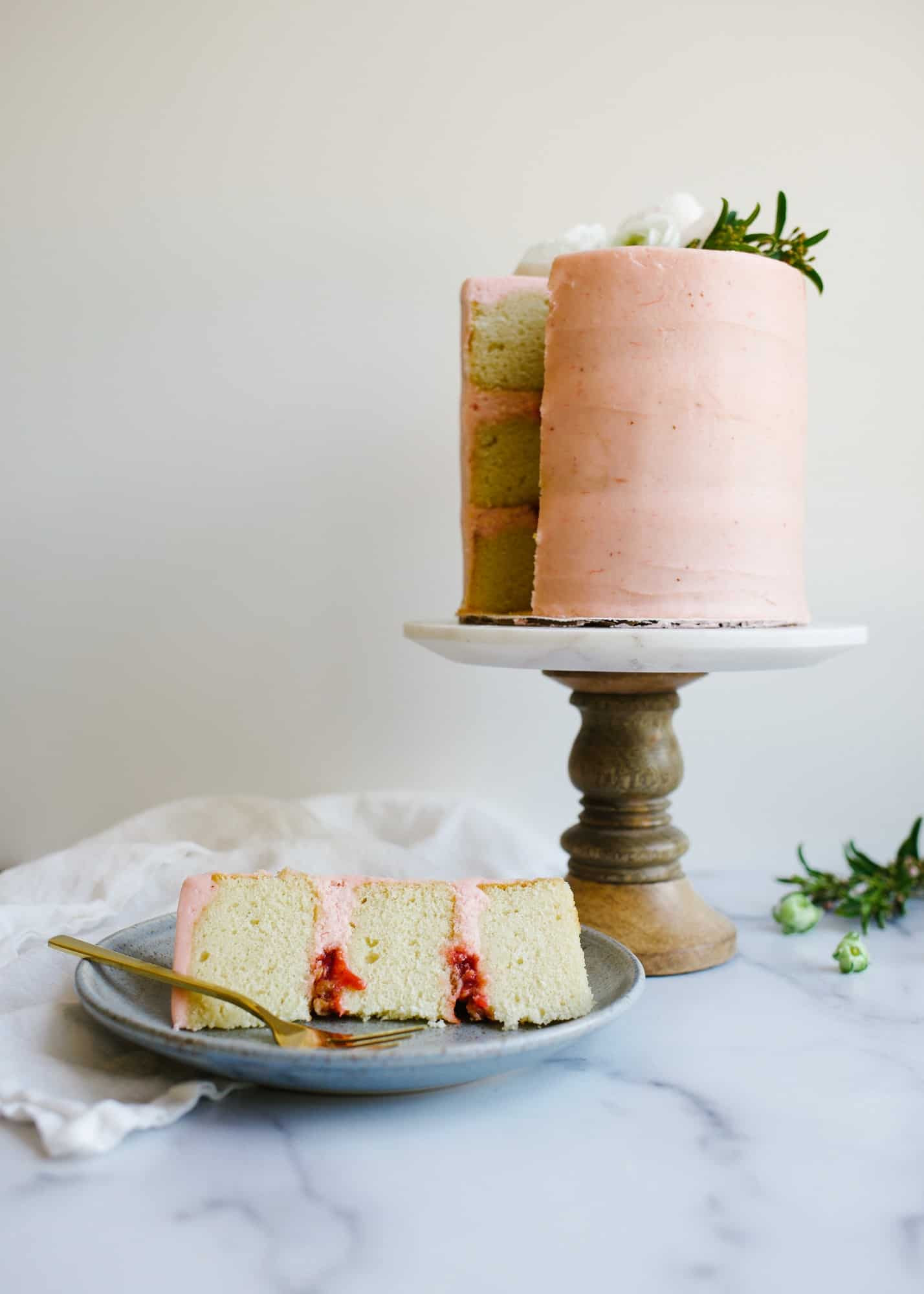 Vanilla Rhubarb Layer Cake by Wood and Spoon. These are vanilla cake layers filled with a rhubarb jam, an oatmeal streusel, and frosted with a rhubarb buttercream. This cake takes on pink color with it's fruit filled icing and stays soft and moist. Perfect for spring and summer parties and celebrations. Find out how to make this naked layer cake on thewoodandspoon.com