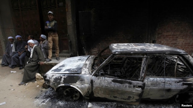 Egyptians sit near a burnt car after clashes between Muslims and Christians in Khusus, El-Kalubia governorate, about 25 kilometers northeast of Cairo, on April 6.