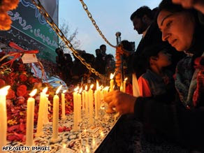 A woman lights a candle Saturday at the site where Benazir Bhutto was killed in Rawalpindi, Pakistan.