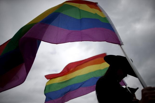 A woman holds rainbow flags for the grand entry at the International Gay Rodeo Association's Rodeo In the Rock in Little Rock, Arkansas, United States April 26, 2015. REUTERS/Lucy NicholsonSEARCH ''RODEO LUCY'' FOR ALL IMAGES