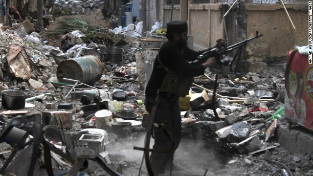 A rebel fighter fires his weapon as he stands amid rubble and debris during clashes with Syrian government forces in Deir Ezzor, Syria, on Monday, November 11.