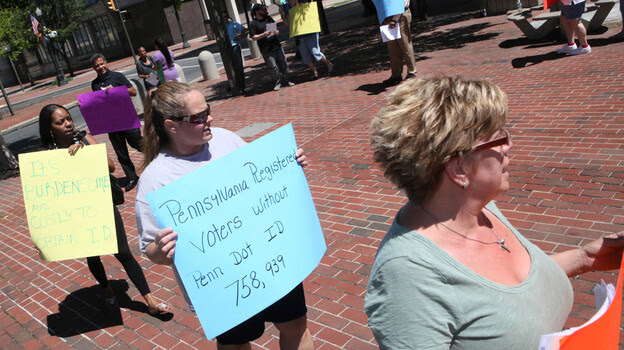 Protesters hold signs in Allentown, Pa., om July 25 as the Commonwealth Court holds hearings on voter ID laws.