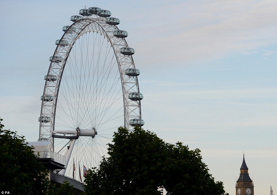 Sky's the limit: The tiny figure of Amelia can be seen atop the London Eye in the blue morning sky over the capital with Big Ben to the right 