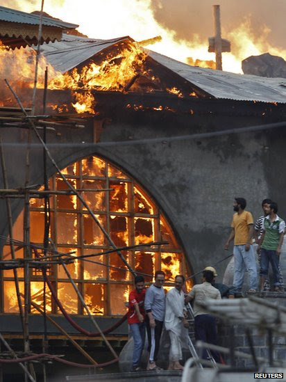 Local residents stand outside a Sufi shrine where a fire broke out in Srinagar