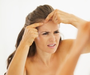 Concerned young woman squeezing acne in bathroom