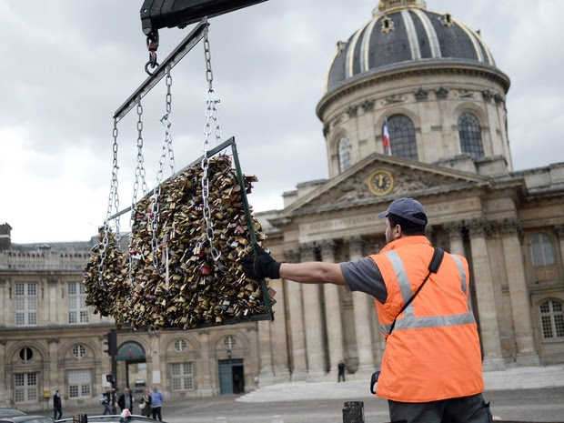 Um trabalhador remove os 'cadeados do amor' da Pont des Arts em Paris, na França. O ritual começou com turistas em 2008 e logo se espalhou para cidades como Nova York, Seul e Londres. Cerca de 1 milhão de cadeados pesando 45 toneladas serão removidos (Foto:  Stephane De Sakutin/AFP)