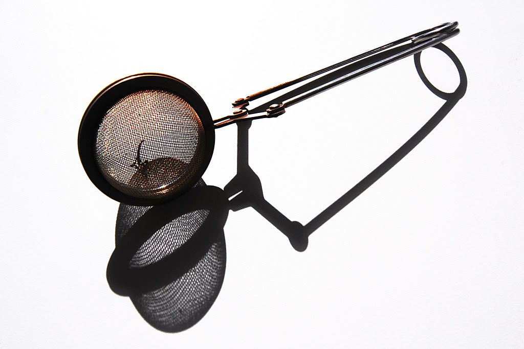 A tea infuser with its shadow.
