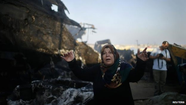 A Palestinian woman reacts after her son's boat is burned in an Israeli naval strike in Gaza City, 11 July