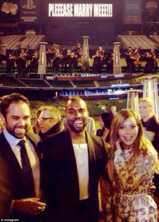 The happy couple: Kim and Kanye pose with a fellow guest as they celebrated with family and friends after the rapper popped the question