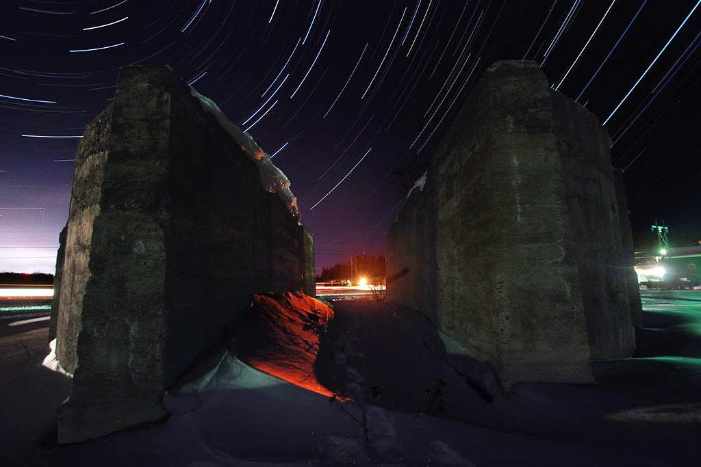 Star trails, through a break in a massive cement foundation.