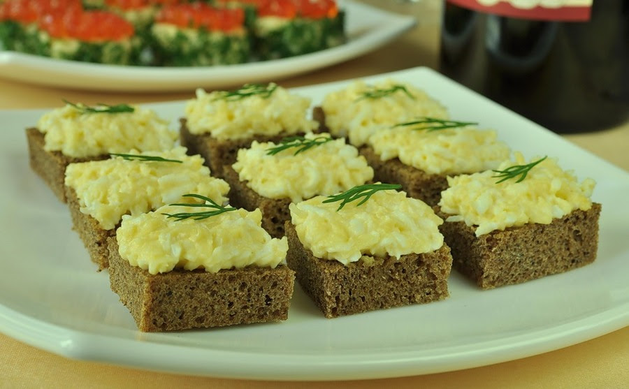 Салат из сыра с вареным яйцом и чесноком и зеленым укропом н кусочку черного хлеба.