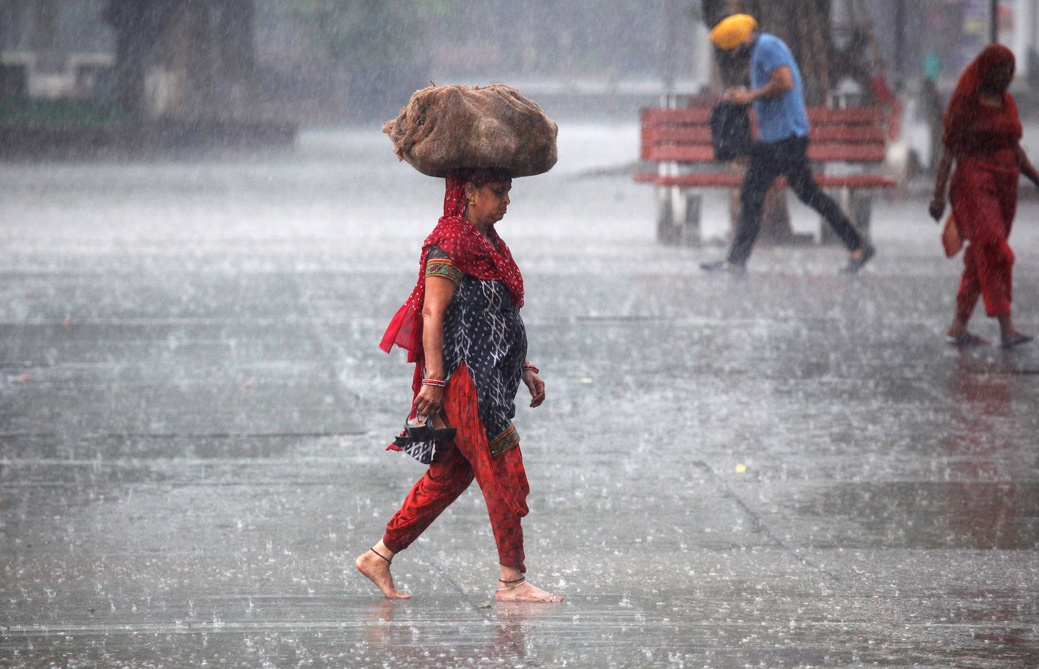 A woman carries a sack outside a market during heavy rains in Chandigarh, India,