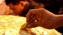 Hands attach gold leaf to the Buddha statue in Mandalay