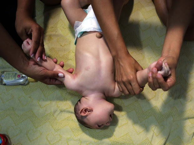 Terapeuta ensina Daniele Santos a fazer a manssagem shantala em seu filho, que nasceu com microcefalia (Foto: REUTERS/Paulo Whitaker )