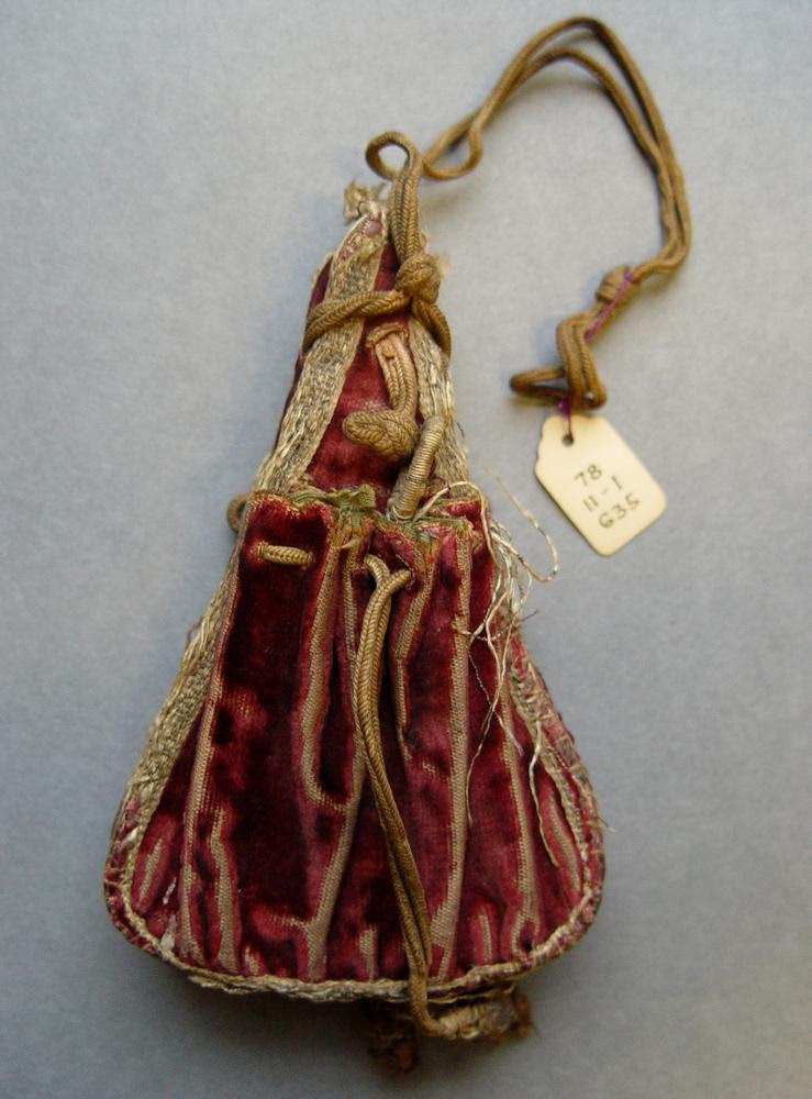 Purse; crimson velvet; in the shape of a powder flask, with stiffened centre padded with horsehair; a drawstring pouch on each side and silver braid round edge.