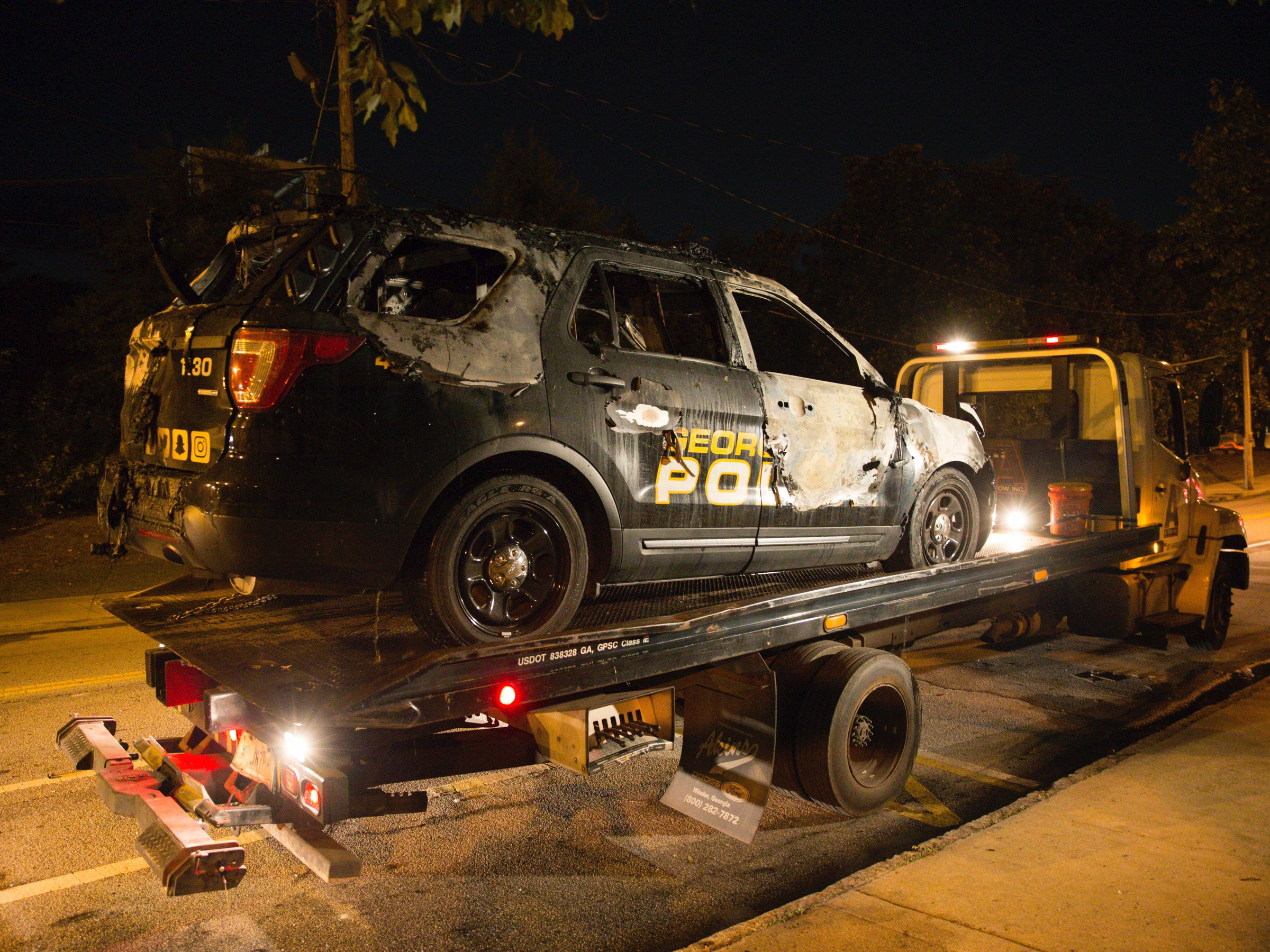 A truck loads a burned Georgia Tech police vehicle in front of the police station on campus in Atlanta on Monday, Sept. 18, 2017. The car was allegedly set ablaze by protesters who were demonstrating against a shooting, which resulted in a fatality, of Georgia Tech student Scout Schultz on Saturday.
