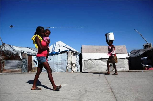 Dos mujeres caminan en el campamento de refugiados Aviación, en Puerto Príncipe (Haití). EFE/Archivo
