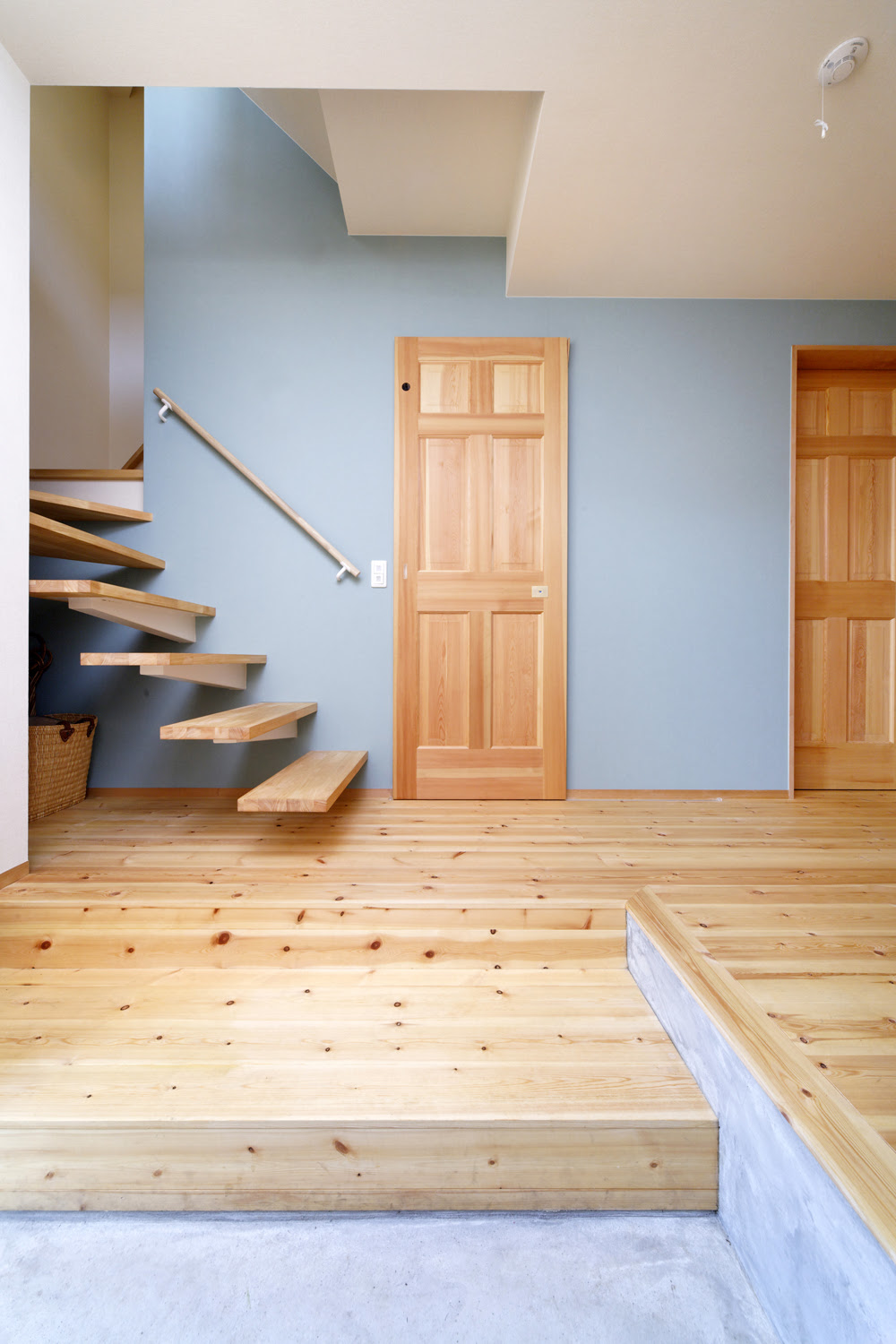壁から突き出た階段とアクセントの壁紙が 訪れる人の目を引きつける玄関ホール Fevecasa フェブカーサ