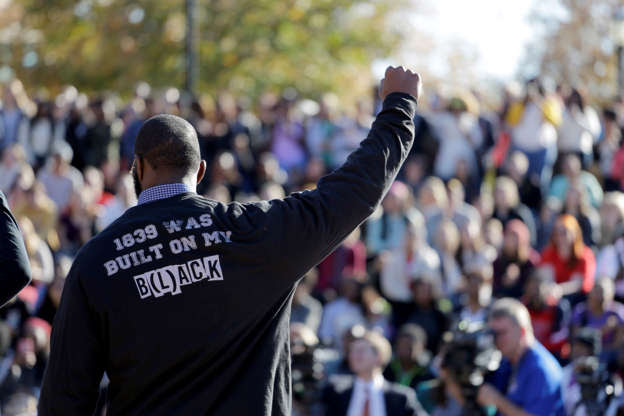 A member of the black student protest group Concerned Student 1950 gestures on Monday while addressing a crowd following the announcement that University of Missouri System President Tim Wolfe would resign, at the university in Columbia, Mo.