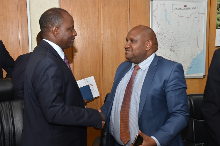 Acting Treasury CS Ukur Yattani (left) speaks to KRA boss James Mburu after their maiden meeting with the tax body.