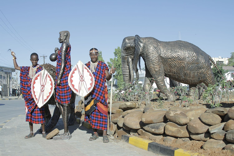 Maasai security guards stand next to a Maasai statue at the Makupa roundabout on Saturday.