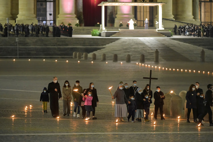 Pope Francis leads the Via Crucis (Way of the Cross) procession in the empty square outside the Saint Peter's Basilica during Good Friday celebrations at the Vatican, April 2, 2021.