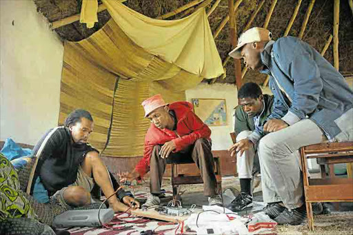 GETTING CONNECTED: Zenzeleni Networks technicians, left, in Mankosi village, Mthatha are hard at work providing a low-energy, low-cost telecommunication service to the community. Right, one of the houses in the village that hosts the nodes used for connnection Picture: SUPPLIED