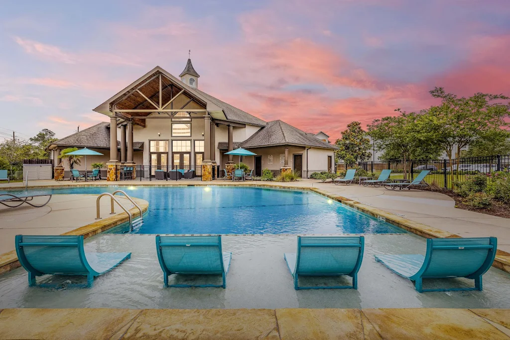 Swimming pool with in-pool lounge chairs and view of the clubhouse at dusk 