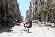 A boy sits on a chair along a damaged street at the city of Douma in Damascus, Syria April 16, 2018.