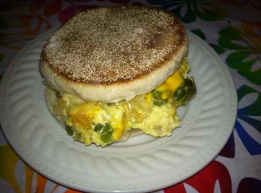 Eggs with onion, green peppers, and cheese on an English muffin.