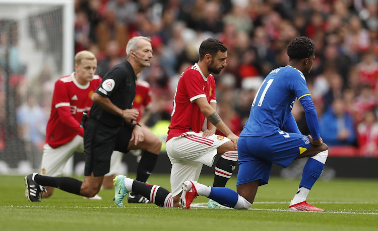 Everton's Demarai Gray, Manchester United's Bruno Fernandes and referee Martin Atkinson take a knee before a pre-season match Between Everton and Manchester United