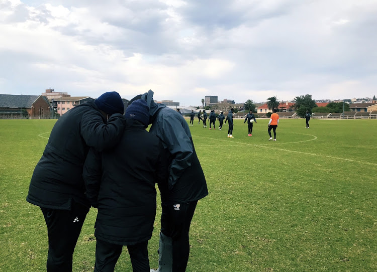 Coaches Morena and Vela huddle to talk analysis with Sinesipho Mali during training warm-up.