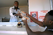 The owner of Kota King helping his customer Moses Ramushu with his bunny chow (Kota), at Kota King, Protia glen Extension 13, Soweto.
