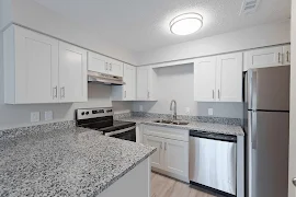 Kitchen with white shaker cabinets, stone inspired counters, stainless steel appliances and light wood inspired flooring