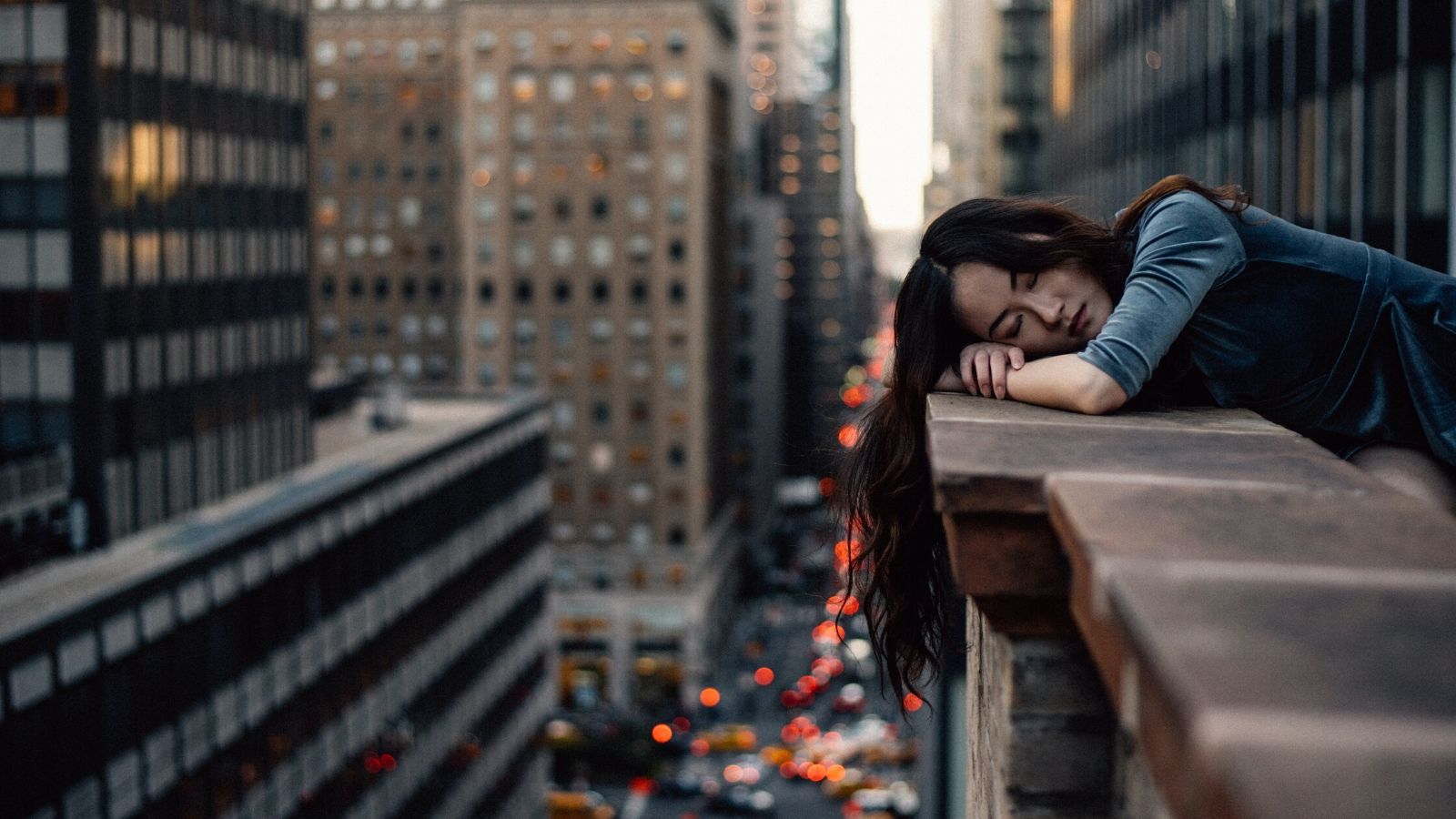A woman sleeps on the balcony of an apartment building.