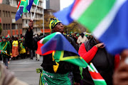 People carrying South African flags gather during the Women’s Day march to the Union Buildings on August 9 2018 in Pretoria.