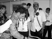 CELEBRATING VICTORY: Adrian Zaugg cutting acake with Tokyo Sexwale after the good showing at the biginning of the AIGP series in Zandvoort, Netherlands. Zaugg will also be driving in the Beijing street race. Pic. Musa Zondi. © Sowetan.