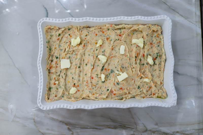 Mashed Potatoes In A Greased Baking Dish With Pats Of Butter On Top.