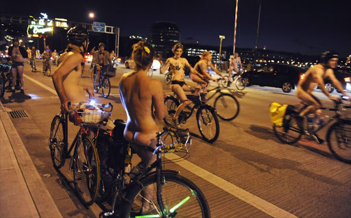 Michael Rutledge (L) and Sarah Lynch pause to watch and applaud as Portland bikers ride in celebration of the annual World Naked Bike Ride in Portland, Oregon June 18, 2011. World Naked Bike Ride is a globally observed event among hard-core bikers designed, at least ostensibly, to promote the use of the bicycle for transportation. But Portland cyclists have been especially adamant about making it another of the Pacific Northwest city's quirky traditions. Picture taken June 18, 2011. REUTERS/Greg Wahl-Stephens