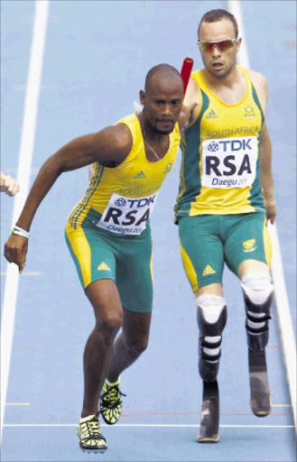 OVER TO YOU: Oscar Pistorius hands the baton to teammate Ofentse Mogawane during their men's 4x400m relay heat yesterday. Photo: REUTERS
