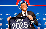 Kylian Mbappe poses with a 2025 Paris Saint-Germain t-shirt at Parc des Princes in Paris on May 23 2022 after signing his new contract.