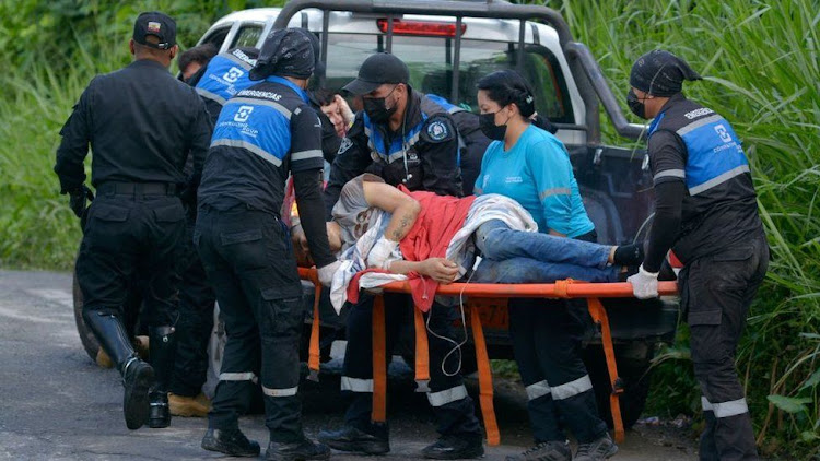 A wounded inmate is moved from a truck to a waiting ambulance by paramedics