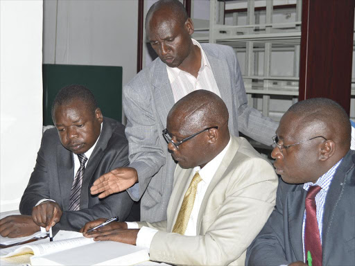 PAC chairman Wilfred Odalo (standing) consults auditors during committee proceedings.