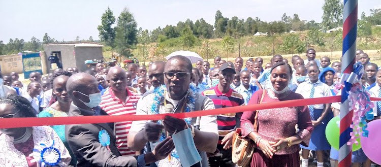 Suna West MP Francis Masara cuts ribbon as he opens an infrastructure at St Francis Wiga Giirls Secondary